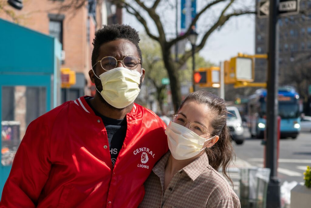 Two people smiling and hugging while wearing masks during the COVID-19 pandemic